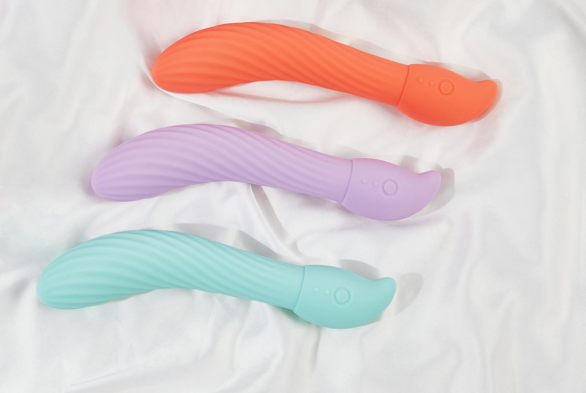 Hand holding a blue silicone vibrator against a purple background, representing solo self-pleasure and personal intimacy.