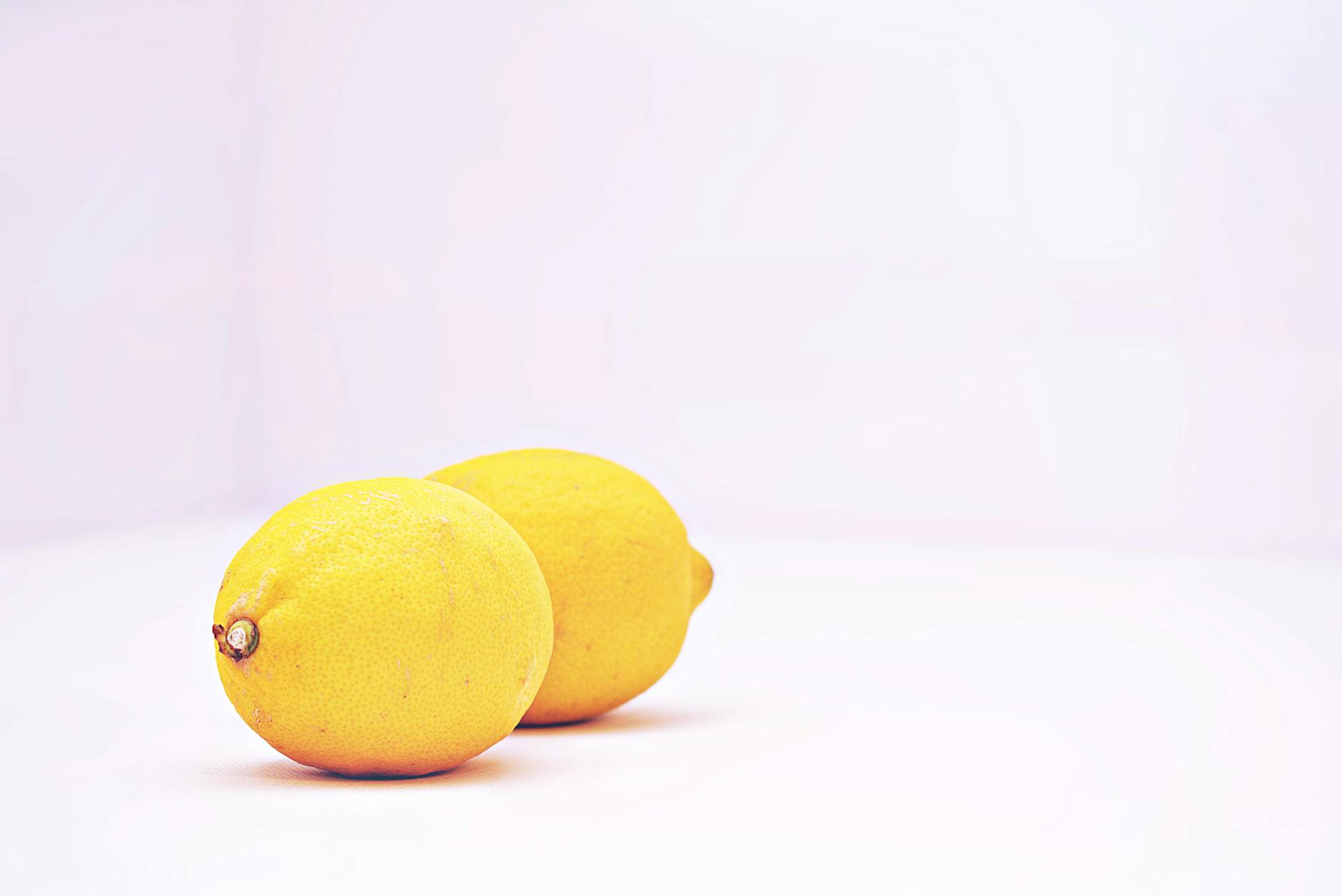 Two vibrant lemons against a white background, symbolizing freshness and self-care