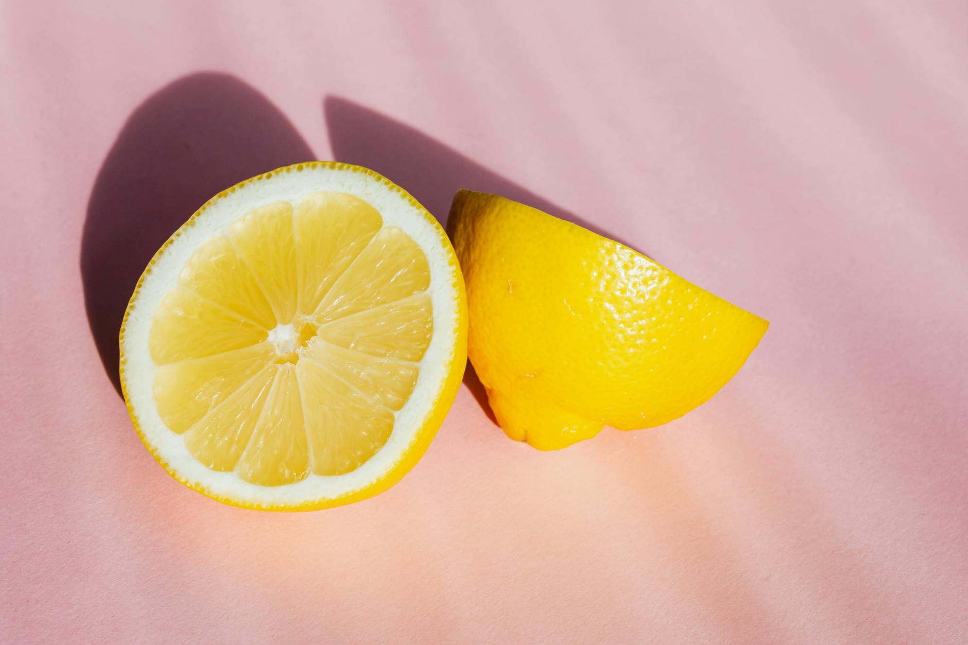 Fresh lemons halved and arranged on a pink background, symbolizing the cyclical nature of hormonal sensitivity.