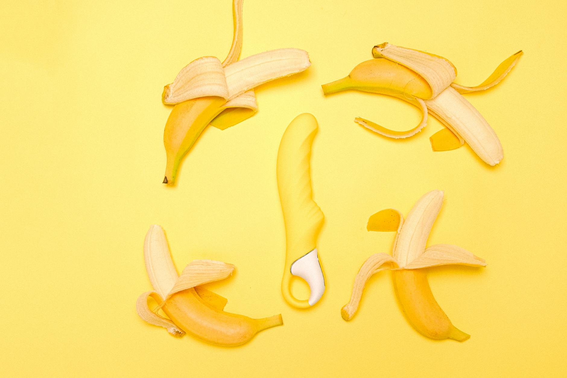 Yellow lemon vibrator surrounded by fresh lemons on bright yellow background
