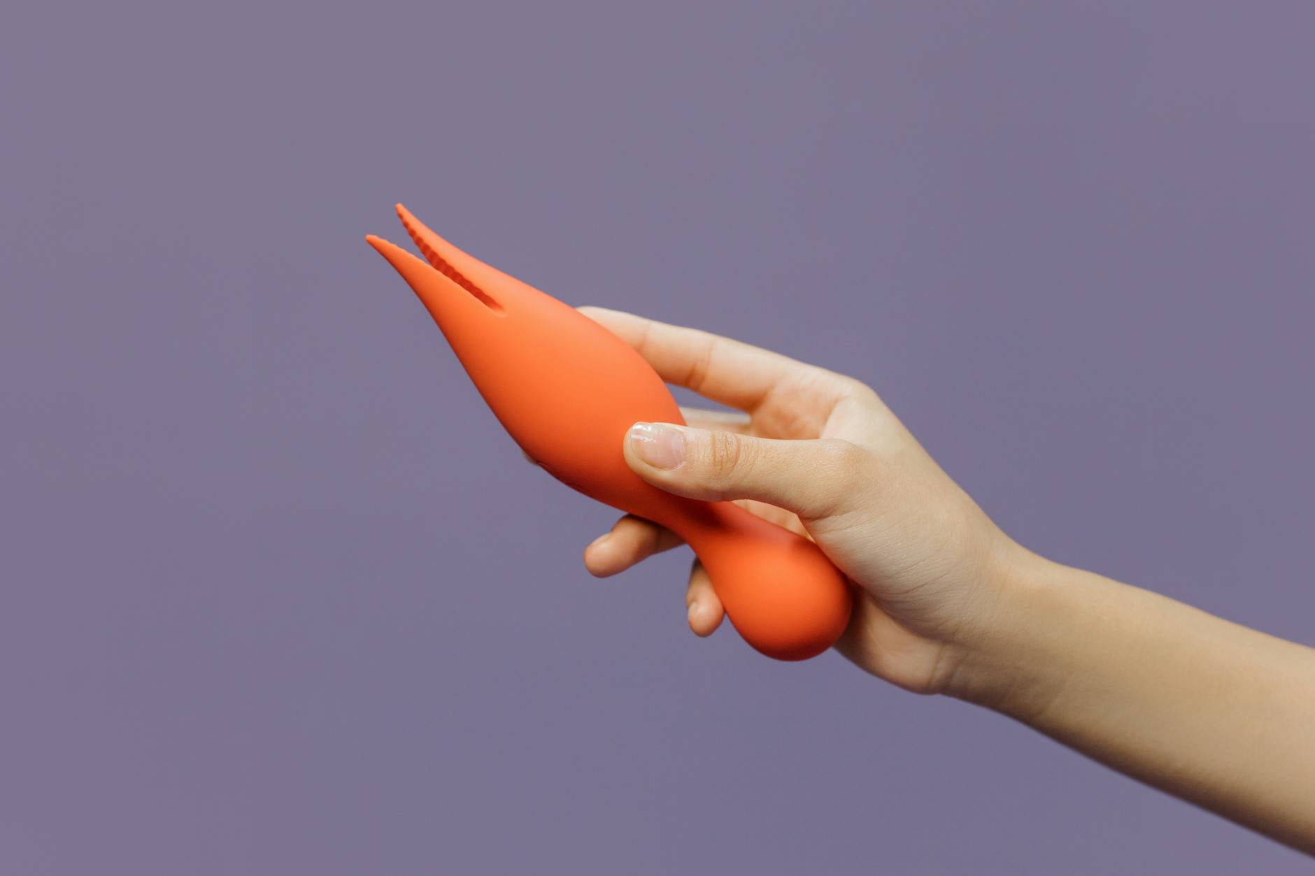 A hand holding a lemon-colored vibrator against a minimalist purple backdrop, symbolizing gentle postpartum sensuality.
