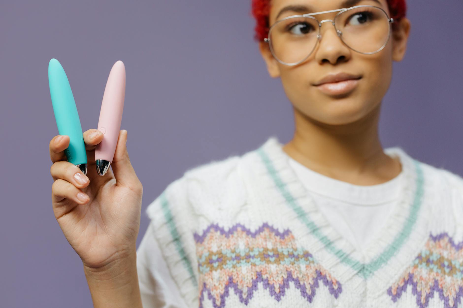 A blue silicone sex toy held in hand against a purple background, showcasing modern clitoral stimulation