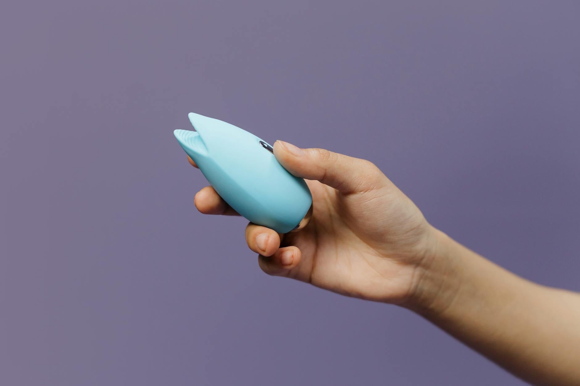 A hand holding a lemon-shaped silicone vibrator against a soft background, symbolizing renewed intimacy and shared pleasure