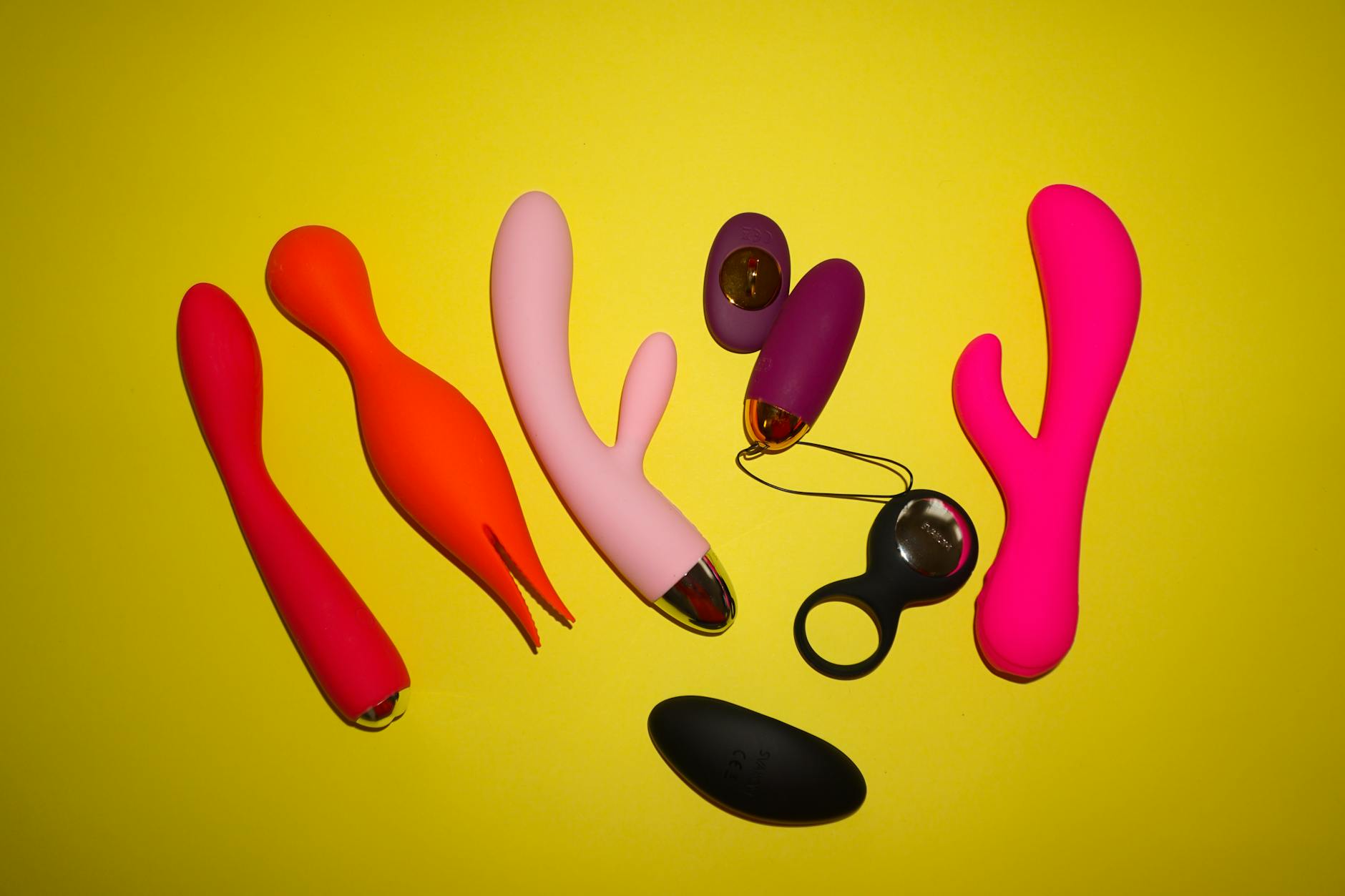 Colorful sex toys arranged on a bright yellow background